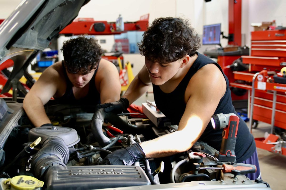 Students Mark Qafi and Christopher Renteria work on a car's engine during their Auto shop class with Mr. Barahona 