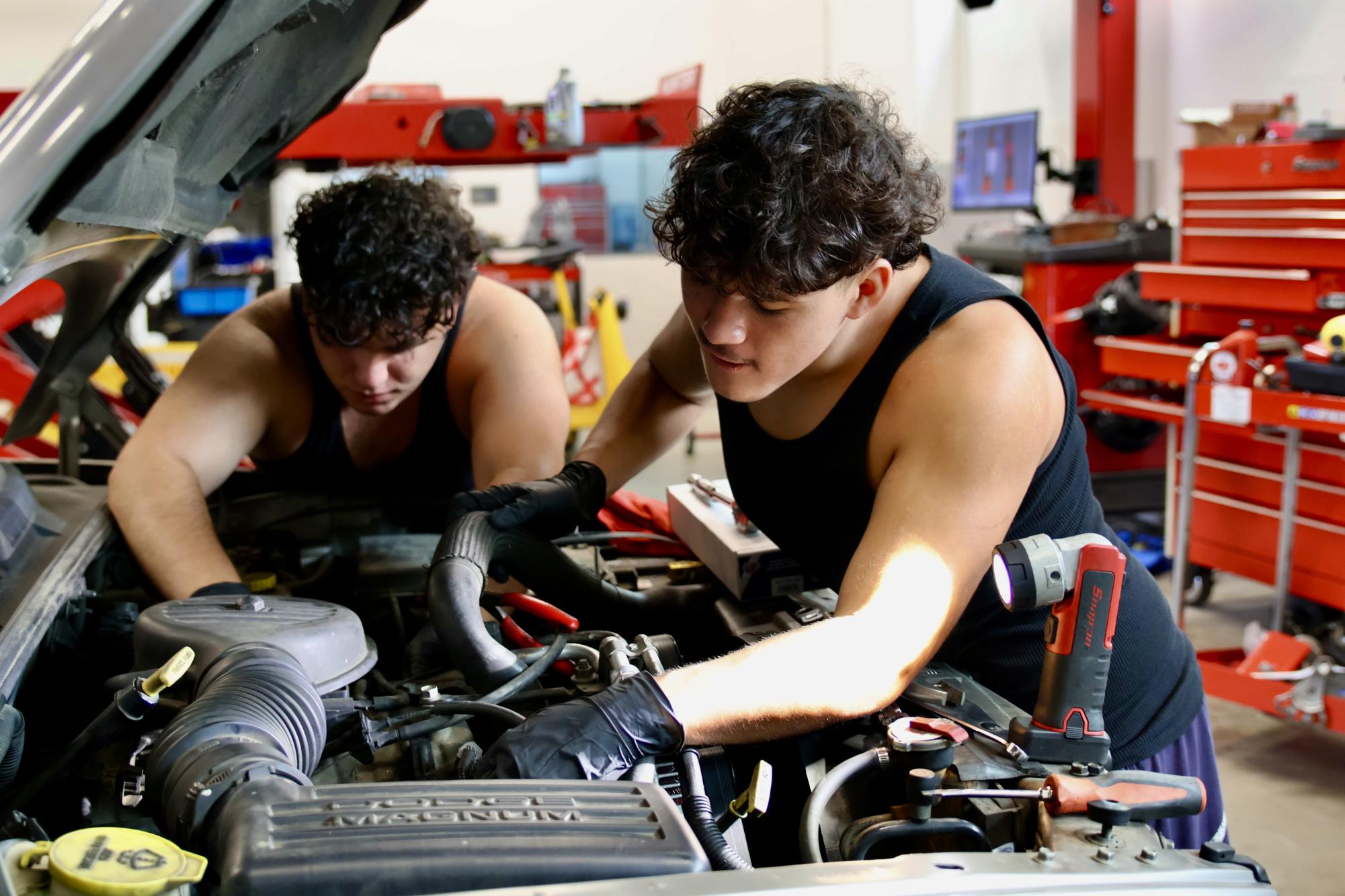 Students Mark Qafi and Christopher Renteria work on a car's engine during their Auto shop class with Mr. Barahona 