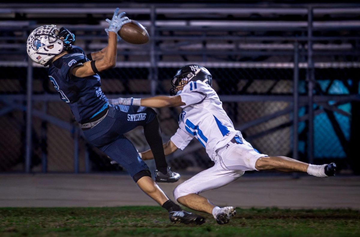A Sylmar High School receiver secures a catch midair as a North Hollywood High School defender lunges to disrupt the play during the first 2025 CIF Division 2 football playoff game, a 42–35 victory.
