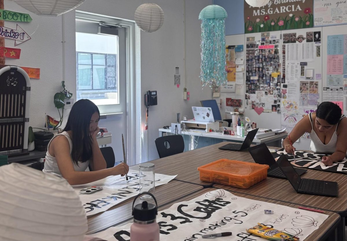 Grace Palmquist and Rosselyn Delucas-Santos working on decorating posters