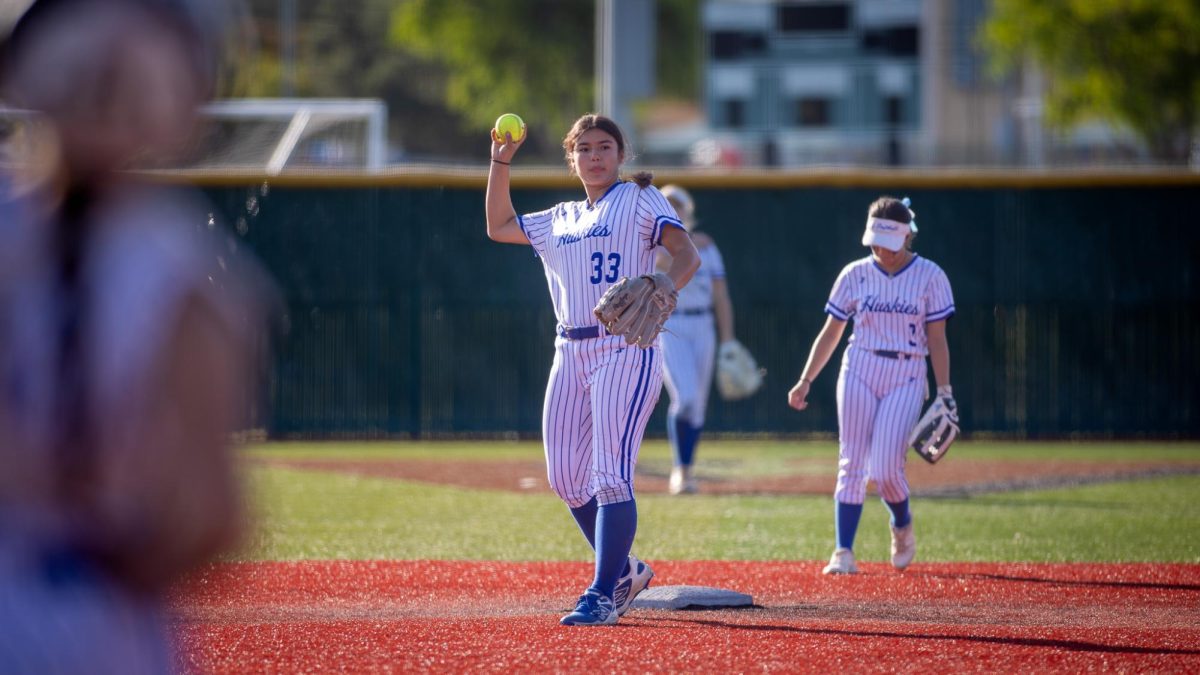After a play from the opposing team, Alison Hernandez (#33) throws softball to catcher Leela Adams (#2).
